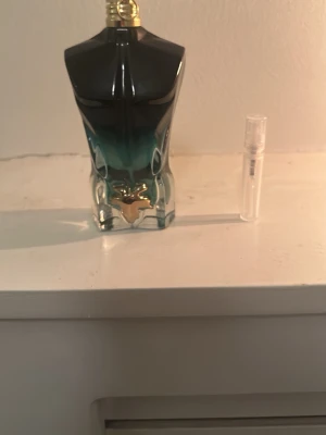 Jean Paul Gaultier Le Male parfym - Säljer en Jean Paul Gaultier Le Male parfym i den ikoniska flaskan formad som en manlig torso. Flaskan har en snygg blågrön gradient och gulddetaljer. Parfymen har en fräsch och maskulin doft, perfekt för dig som vill sticka ut.
