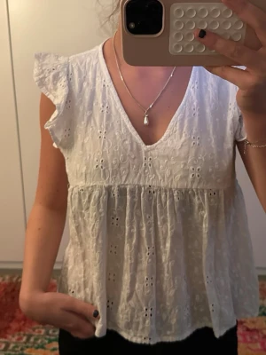 Vit blus med spets och volangärm - Söt vit blus med broderade spetsdetaljer och volangärmar. Blusen har v-ringning 