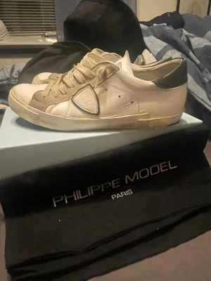 Philippe Model vita sneakers med svart detalj - Snygga vita sneakers från Philippe model köpta ifrån merch sweden box o allt og ingår det är storlek 43 kan även passa en 44 OBS defekt på sulan men de går nog att göra en Quick fix på de men något lim, pris o sånt kan diskuteras såklart🙌