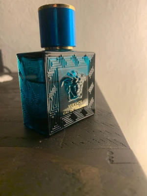 Versace Eros Eau de Toilette - Versace Eros Eau de Toilette med en snygg blå flaska och guldiga detaljer. Perfekt för dig som vill sticka ut och ge din stil en extra edge. Flaskan har en modern design med Medusa-symbolen framtill. Och har mer en halva kvar 