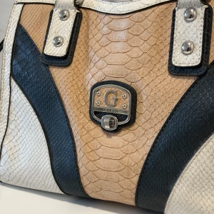 Guess väska - Supersnygg guess väska I konstmaterial! I svart, benvit och cremefärg. Jättefint begagnat skick. 