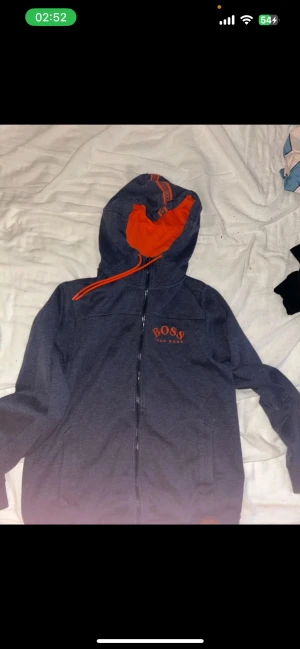 hugo boss tröja  - .Säljer en Hugo Boss hoodie i storlek M i blå/grå färg med orange detaljer. Det här är en svårfunnen modell som inte säljs längre, vilket gör den extra eftertraktad. Tröjan är i nästan nyskick, väldigt lite använd och helt utan skador.Säljer en Hugo Boss hoodie i storlek M i blå/grå färg med orange detaljer. Det här är en svårfunnen modell som inte säljs längre, vilket gör den extra eftertraktad. Tröjan är i nästan nyskick, väldigt lite använd och helt utan skador.
