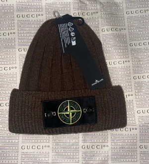 Stone Island ribbstickad mössa - Ribbstickad mössa från Stone Island med ikonisk kompasslogga framtill på svart patch. Finns i olika färger Klassisk uppvikt kant och mjukt material som håller dig varm och snygg hela vintern.