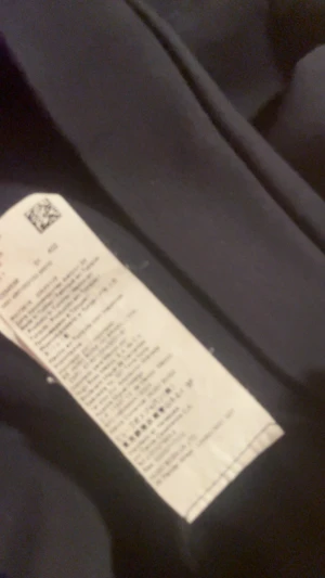 Svart hoodie från BOSS med snörning - Svart hoodie från BOSS med vit kant runt huvan och diskret logga på bröstet. Tröjan har snörning i huvan med gröna detaljer på ändarna och en klassisk känguruficka framtill. Materialet är mjuk bomull och polyester, perfekt för chill dagar.