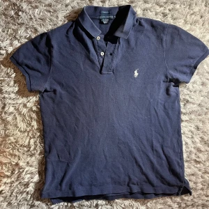 Marinblå pikétröja från Ralph Lauren - Pikétröja från Ralph Lauren i topp skick säljes! Inga defekter sparsamt använd. Skick 9/10! Passar perfekt som XS eller S även fast pikén är M, AB = 40 cm och L = 60 cm. Priset kan diskuteras vid snabb affär! Hör av dig om du har frågor eller vill ha fler bilder! 🤝👏