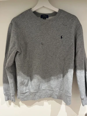 Grå sweatshirt från Polo Ralph Lauren - Tröja från Ralph lauren i storlek 14/16 som motsvarar xs/s! Väldigt bra skick inga skador eller liknade! Hör av vid minsta fundering! 