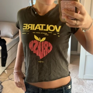 Grön tour t-shirt Zadig & Voltaire - Cool grön t-shirt från Zadig & Voltaire med tryck i gult och rött framtill och turnédatum på ryggen. Modellen är croppad med korta ärmar och har en edgy, lite rå kant vid halsen. ❤️