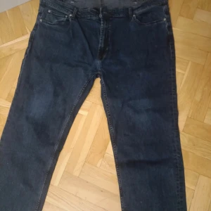 Mörkblå jeans från Dressmann 44/30 - Säljer ett par mörkblå jeans från Dressmann i klassisk femficksmodell. Jeansen har rak passform och normal midja, tillverkade i slitstarkt denimtyg. Perfekt för dig som gillar enkel och tidlös stil.