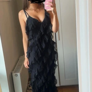 Svart långklänning med volanger - Säljer min sååå fina klänning pga den inte kommer till användning! Använd 1 gång under min bal, storlek 36 och den har även justerbara band så går att göra kortare eller längre vid behov! Jag är ca 170 för referens ❣️❣️❣️ Hör av er vid frågor eller om fler bilder önskas 🥰