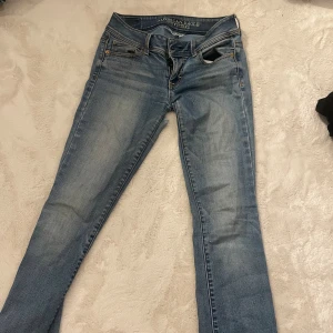 Blå jeans från American Eagle - Snygga blå jeans från American Eagle Outfitters med super stretch. Klassisk femficksdesign, ljus tvätt. De har hål men det går att laga, säljer därför billigt man ser på bilden. Bra på mig i längden som är 170 och passar som va strorlek 34/ xs