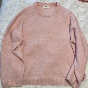 Ljusrosa stickad tröja Gina Tricot - Mysig ljusrosa stickad tröja från Gina Tricot i ullblandning. Tröjan har rund hals, ribbade muddar och långärmad passform. Perfekt för dig som gillar enkel och clean stil med en soft vibe.