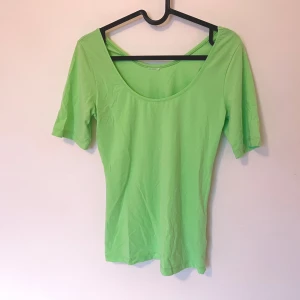 Grön topp med rund hals från Gina Tricot - Snygg ljusgrön tröja med en djup U-ringning. Den sitterfigurnära men är inte insydd. Bra kvalitet utan tydliga defekter. Mått finns om så önskas, lapp var avklipp men den passar S & M.