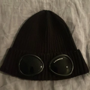 Svart C.P. Company mössa - Säljer denna feta cp company mössan då jag mest använder en annan. Har använts några gånger men är i väldigt bra skick, självklart äkta också. Perfekt nu är inför vintern ❄️👀🔥