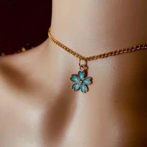 By prisförslag- Guldhalsband med blå blomma - Choker-halsband i guld med en söt blå blomberlock. Blomman har fem kronblad och en liten glittrande sten i mitten. Kedjan är tunn och elegant, perfekt för att ge en färgklick till din stil.