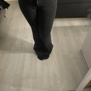 Svarta lågmidjade bootcut jeans - Säljer ett par svarta jeans med bootcut-modell. Jeansen har en snygg passform som sitter tajt upptill och släpper ut vid benen. Perfekta för dig som gillar en stilren look med lite edge.