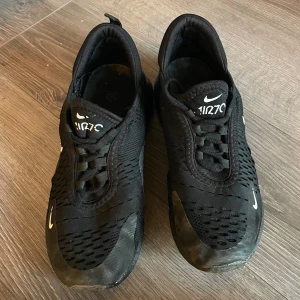 Nike Air Max 270 svarta sneakers 39 - Svarta Nike Air Max 270 sneakers med vit logga och textdetaljer. Skorna har mesh-ovandel för bra ventilation, skorna är ej äkta därför priset storlek 39