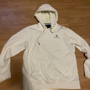 Vit hoodie från Bondelid  - Vit hoodie från Bondelid med broderad logga på bröstet. Tröjan har huva med snörning och ribbade muddar vid ärmslut och nederkant. Perfekt för en chill och stilren look. Storleken är M men passar som S