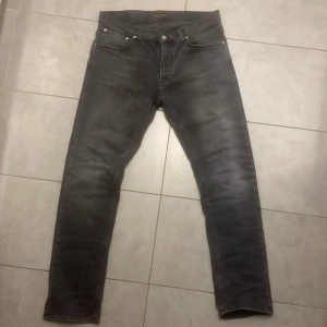 Svarta jeans från Nudie Jeans Co, 34/34 - Snygga svarta jeans från Nudie Jeans Co i storlek 34/34. Jeansen har klassisk femficksdesign, svarta sömmar och en något tvättad look. Helt nya typ använda max 2 gånger, Perfekt passform med raka ben och diskret logga på bakfickan. Tillverkade i mjukt och slitstarkt bomullstyg.