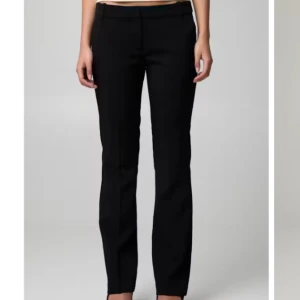 Svarta kostymbyxor - Snygga lågmidjade kostymbyxor med bootcut passform och klassisk midja. Byxorna har bälteshällor och en stilren look som passar perfekt till en dressad outfit. Materialet är mjukt och ger en skön känsla hela dagen.