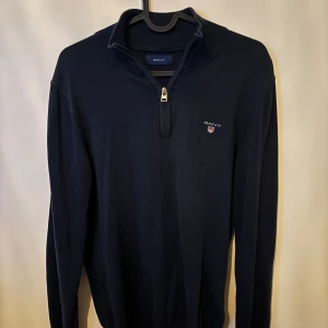 Marinblå half zip tröja från GANT - Hej, säljer den här marinblåa tröjan från GANT. Tröjan är i bra skick och säljs på grund av att den inte används. Tveka inte på att höra av dig vid frågor!