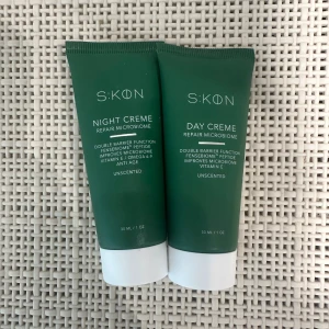 S:KØN Night & Day Creme duo - Två gröna tuber med S:KØN Night Creme och Day Creme, båda 30 ml. Oparfymerade och innehåller peptider, vitamin E och omega 6-9. Tuben är grön med vit kork och text i vitt. Perfekt för dig som vill boosta hudens mikrobiom och barriärfunktion.