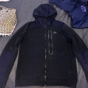Sällsynt Nike Tech Fleece Svart/Reflektiv - Sällsynt Nike Tech Fleece zip hoodie med en bröstficka, Reflektiv på armarna, övre rygg och luvan, Storlek Medium, väldigt bra skick. Pris går att diskutera vid snabb affär!