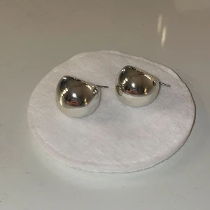Örhängen   - Säljer ett par silvriga dropp örhängen. De har en modern vibe och är riktigt statement med sin glansiga yta. Perfekta för dig som gillar att sticka ut med accessoarer som syns.