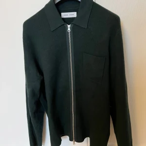 Mörkgrön kofta från Samsøe Samsøe - Snygg mörkgrön kofta från Samsøe Samsøe med klassisk krage och silverfärgad dragkedja framtill.     Bra skick och storlek L