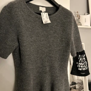 Grå stickad topp med volang från H&M - Superfin grå stickad topp från H&M som är korta ärmar. Tröjan har en volang nedtill ❤️köpte den i förr igår för 239 aldrig använd bara privat den. De är i stork L men skulle säga att det är en M(dom på hm sa gå upp en storlek)