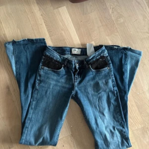 Blå bootcut jeans - Snygga blå jeans från ltb med bootcut passform och svarta detaljer på framfickorna. Jeansen har klassisk femficksdesign, låg midja och är tillverkade i mjukt denimtyg. Köpte på Vinted men passade inte. Omsydda till bootcut. Midjemått rakt över: 32 cm Innerbenslängd: 80 cm❤️