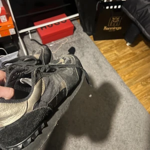 Valentino Garavani Rockrunner sneakers - Svarta och guldiga Valentino Garavani Rockrunner sneakers. Skorna har en mix av mocka och skinn,. Skorna e givetvis äkta men har tyvärr ingen box elr så, och som man ser e skorna ganska slitna men funkar fortfarande att använda helt perfekt därav priset, vilket även går diskutera 