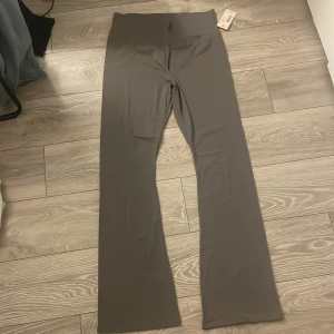 Grå Soft Chill Pants från Nelly XL - Gråa Soft Chill Pants från Nelly i storlek XL. Byxorna har hög midja och är tillverkade i ett mjukt, stretchigt material. De har raka ben med en lätt utsvängd passform som ger en chill och avslappnad vibe. Perfekta för en bekväm och stilren look. ett par yoga pants 