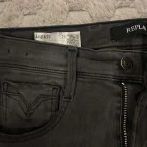 Replay Anbass svarta skinny jeans - Svarta Replay Anbass jeans med skinny passform och klassisk femficksdesign. Jeansen har dragkedjegylf, bälteshällor och diskret Replay-logga. Materialet är mjukt och stretchigt jeans, perfekt för en snygg och bekväm look.