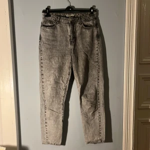 Vitgrå jeans - Vitgråa jeans. Högmidjade. Storlek 38. Relativt gott skick men med ett par små fläckar och lite slitna fickor, inga hål och inga tydliga fläckar.