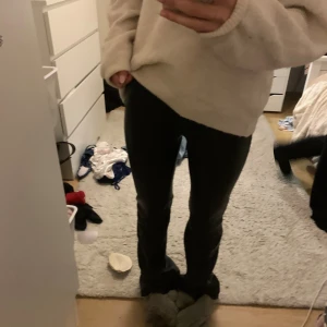 Svarta skinnbyxor - Snygga svarta byxor i skinnimitation med utsvängd passform och högre midja. Byxorna har klassisk femficksdesign och stängs med dragkedja och knapp. Perfekta för dig som vill ha en edgy och trendig look.