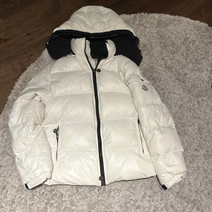 Vit Moncler pufferjacka med huva ( LÄS ANNONSEN!) - Nu säljer jag min Moncler jacka! 🧥. Den är tidigare använd av någon annan säljare så den e inte så ny tyvärr 😔. Den är 12A-152 men sitter på mig som är 160! Skriv om funderingar!❤️👌🏼🔥Modelen kallas för Bazillé. Den har inte DIST lappen för det är en barn jacka👌🏼 OBS! Den har gula fläckar lite över allt! Kan prova o tvätta innan