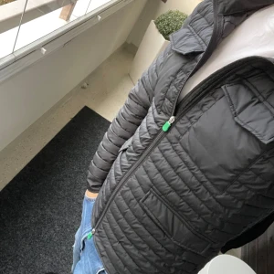 Save the duck jacka M-L - Säljer en svart dunjacka från Save the Duck med grönt logomärke på ärmen. Jackan har quiltad design, dragkedja med gröna detaljer och flera fickor framtill. Perfekt för dig som vill ha en lätt och snygg jacka med modern look.