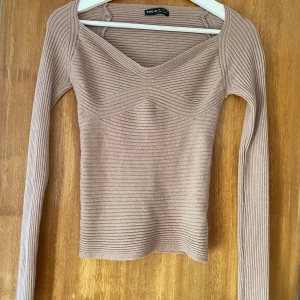 Beige ribbad topp  - Säljer en beige ribbad långärmad topp från SHEIN med snygg v-ringning och figurnära passform.