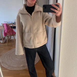 Beige teddyjacka med dragkedja/ höstjacka - Storlek M, men är liten j stoleken. Som referens brukar jag ha storlek xs/s i jackor!  Mysig beige teddyjacka med hög krage och dragkedja framtill. Jackan har två stora fickor och en avslappnad passform som ger en chill vibe. Perfekt för kyliga dagar när du vill vara både varm och snygg.