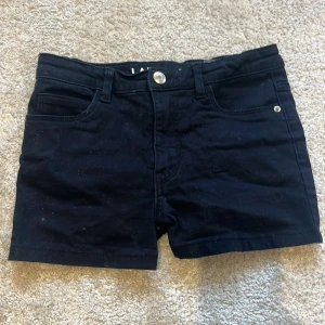 Svarta jeansshorts från LAB Industries - Svarta jeansshorts från LAB Industries med klassisk femficksdesign och knappstängning. Shortsen är tillverkade i ett hållbart denimtyg och har bälteshällor samt raka ben. Perfekta för en chill sommardag eller när du vill ha en enkel och stilren look. Kontakta för fler bilder 🩷