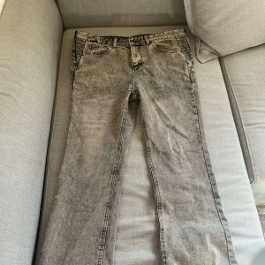 Grå tvättade jeans med raka ben - Säljer ett par grå jeans med snyggt tvättad look och raka ben. Klassisk femficksmodell med bälteshällor och dragkedja. Jeansen har en avslappnad passform och passar perfekt till en streetig stil.