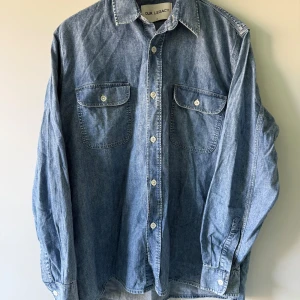 Our Legacy - Jeansskjorta - 48 - Säljer en klassisk blå jeansskjorta från Our Legacy med två bröstfickor och vita knappar. Den är helt ny, har aldrig använt den. Vill helst att köpt vara hämtas på Södermalm i Stockholm.