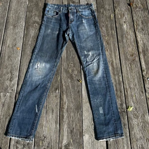 Dsquared2 jeans - Dsquared2 jeans med straight fit och slitna detaljer. Jeansen har fem fickor, knappgylf och snyggt tvättad finish med slitningar på ben och bakfickor. Perfekta för en avslappnad och cool look.