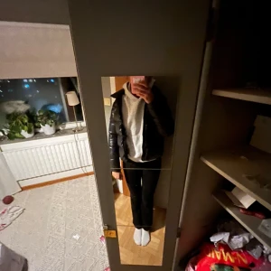 Svart pufferjacka från comlar - Säljer en svart, glansig pufferjacka från colmar. Jackan har en klassisk quiltad look och en rund logotyp på ärmen. Håll i bägge fickorna men går att sy enkelt