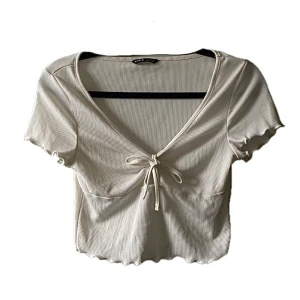 Crop top m rosett - Söt vit topp me rosett detalj! Lite sliten precis vid armhålorna men inget man märker av. 