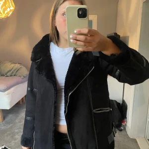 Svart pälsjacka med dragkedjor - Säljer en svart pälsjacka från pull&bear i strl L med bred krage och fluffig insida, Jackan har flera silvriga dragkedjor och en loose passform. Perfekt för dig som gillar en mysig och varm jacka till hösten!💞
