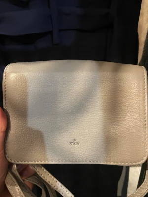 Axelväska från ADAX i läder - Säljer denna fina och praktiska väskan från ADAX. Väskan har fack som stängs med dragkedja. Väskan är grå/beige i färgen och är gjord i läder. Nypriset för denna väska är ungefär 1500kr men eftersom den här har använts säljer jag den för 999kr! Den säljs i befintligt skick då den har använts, men på ett sparsamt och försiktigt sätt. Hör av dig vid intresse🤗