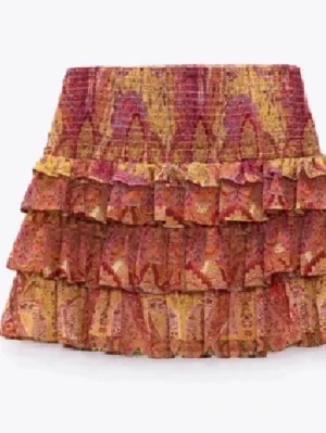 Mönstrad volangkjol zara - Kort kjol med flera volanger i ett färgstarkt mönster med inslag av rött, gult och orange. Kjolen har en bohemisk vibe och är perfekt för dig som vill sticka ut. Tillverkad i ett lätt material som känns skönt mot huden.