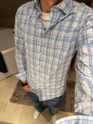 Blåvit rutig skjorta The Shirt Factory - Säljer en klassisk blåvit rutig skjorta från The Shirt Factory. Skjortan har lång ärm, knappar framtill och en snygg krage. Perfekt till jeans eller chinos för en clean look. Storlek 38 och jag på bilden är 183 cm