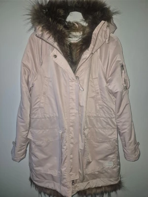 Ljusrosa parkas från Odd Molly med päls, storlek 38/40! - Säljer en ljusrosa parkas från Odd Molly med stor huva och päls både i huvan och som foder. Jackan har flera fickor, dragkedja och knappar framtill samt snygg detalj med Odd Molly-logga på ärmen. Perfekt för kalla dagar och riktigt mysig att bära.              Storlek 38/40.                                                            Mycket fint skick.                                                            Djur och rökfritt hem 